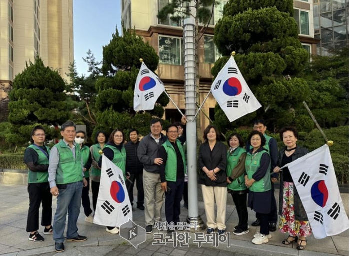 지역 주민들과 시의회 의원들이 국기를 게양하여 애국심과 공동체 정신